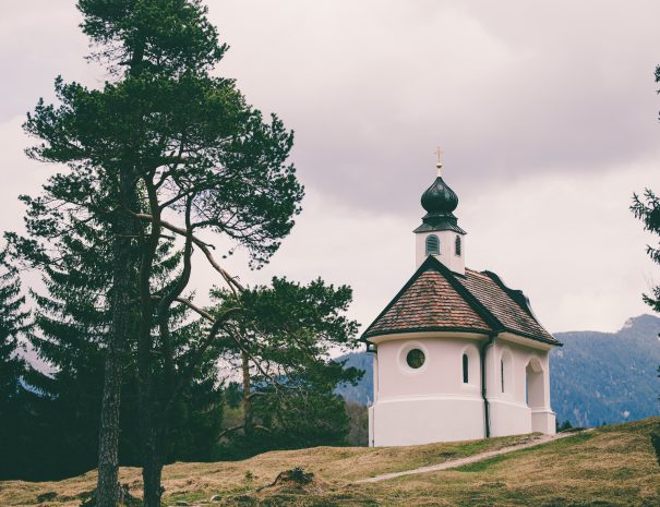 A beautiful small catholic church in the mountains of the Bavarian Alps near the Lautersee and Mittenwald. Cloudy mountain panorama